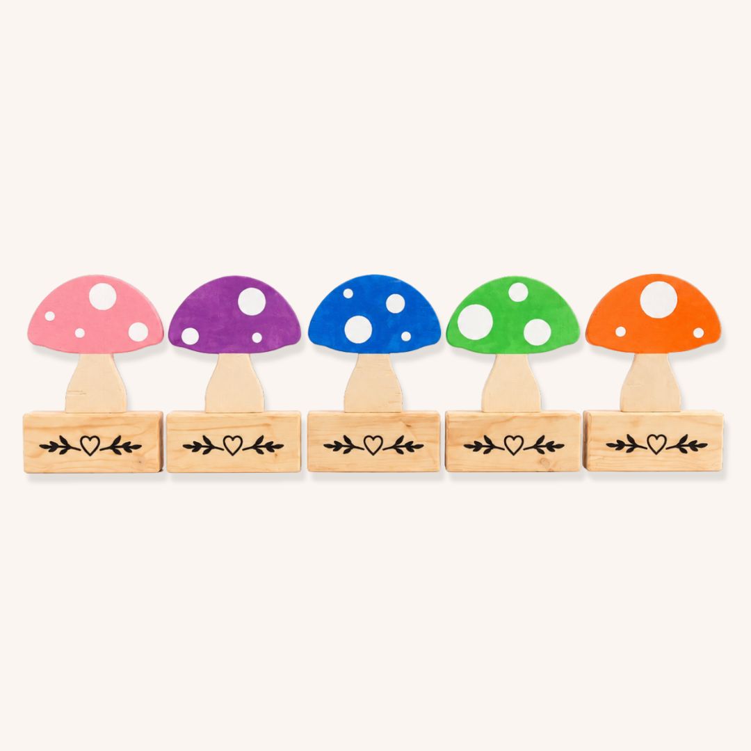 Five colourful wooden mushroom show jump fillers with individual custom pine bases on a plain background