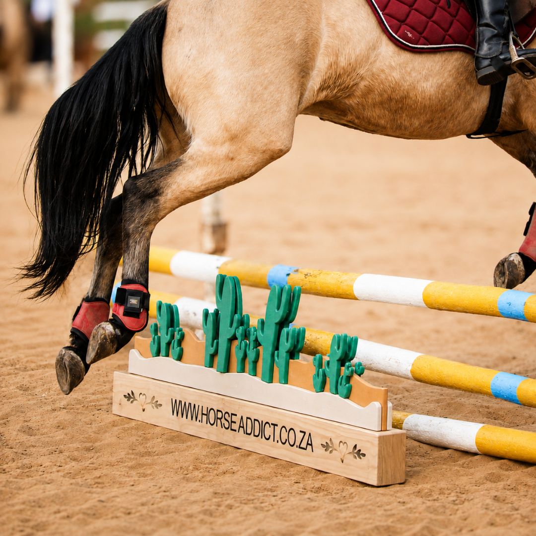 Close view of horse jumping beside a layered green cactus jump filler with custom pine base