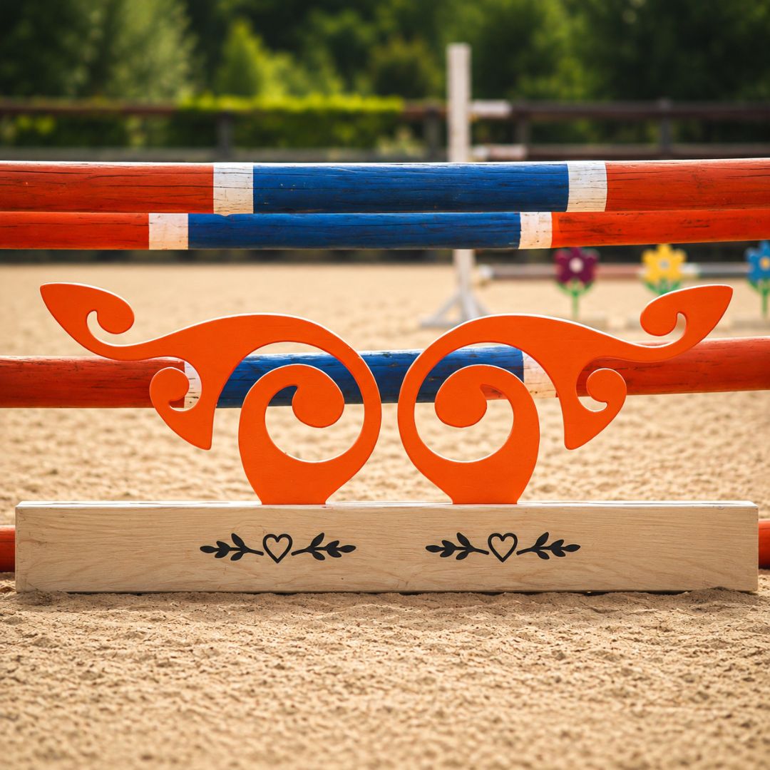 Close front view of orange scroll wooden jump filler with curved cut-outs and custom pine base beneath arena poles